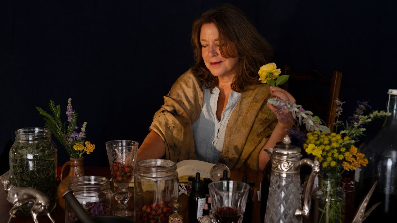 woman working at table with herbs and flowers